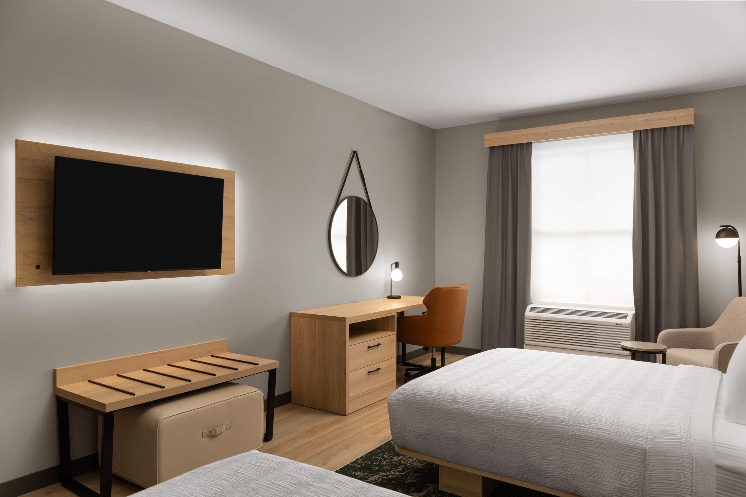 Una habitación de hotel moderna con una cama, un escritorio, una silla y un televisor de pantalla plana en la pared.