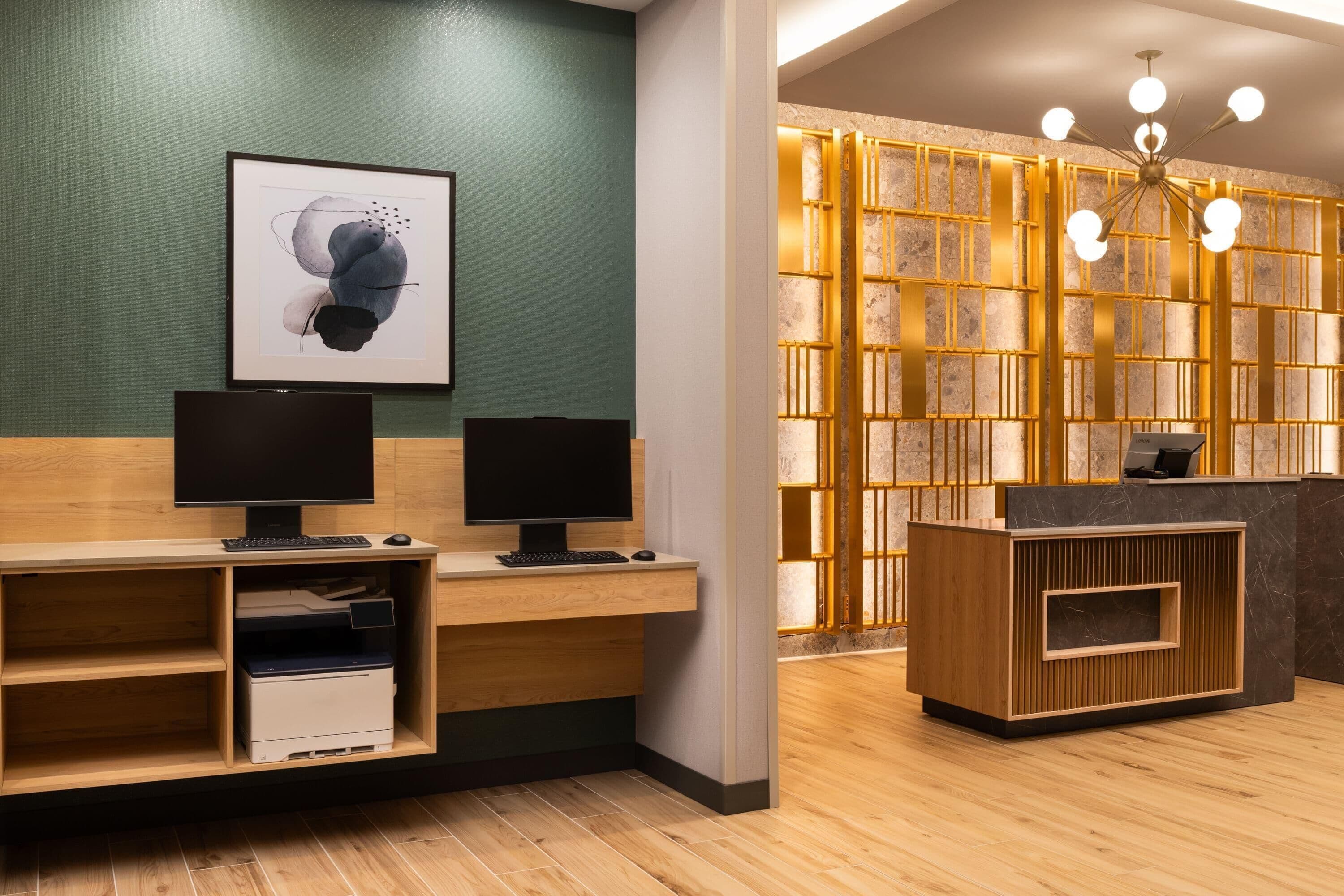 A reception desk with a computer, a framed abstract artwork, and a wooden reception area.