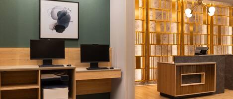 A reception desk with a computer, a framed abstract artwork, and a wooden reception area.