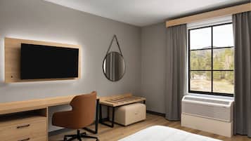 A modern hotel room with a flat-screen TV, a desk with a chair, a window with curtains, and an air conditioning unit.
