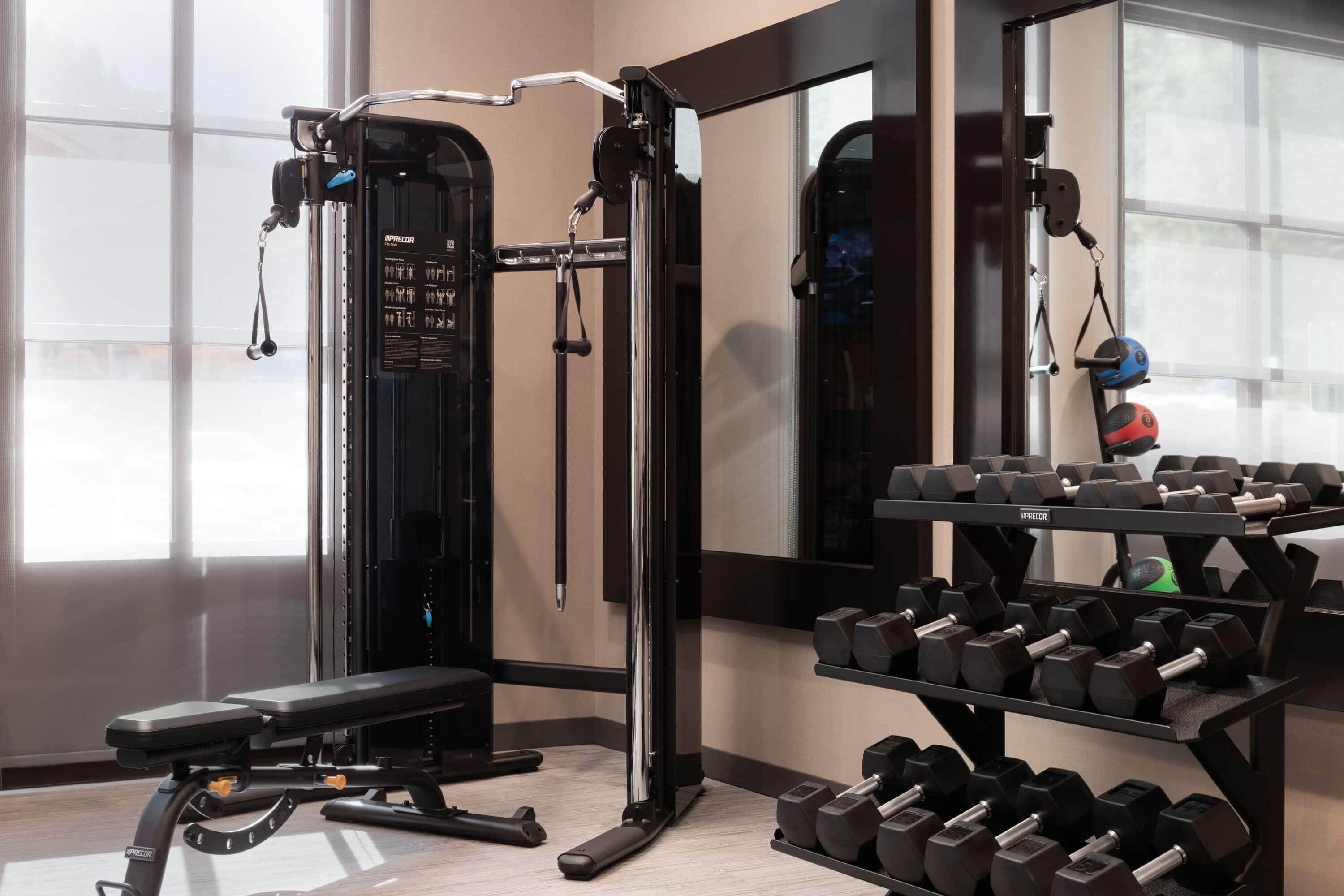 A gym with weightlifting equipment, a bench, and dumbbells.