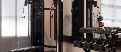 A gym with weightlifting equipment, a bench, and dumbbells.