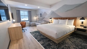Een moderne hotelkamer met een groot bed, een bureau, een bank en uitzicht op de omgeving.