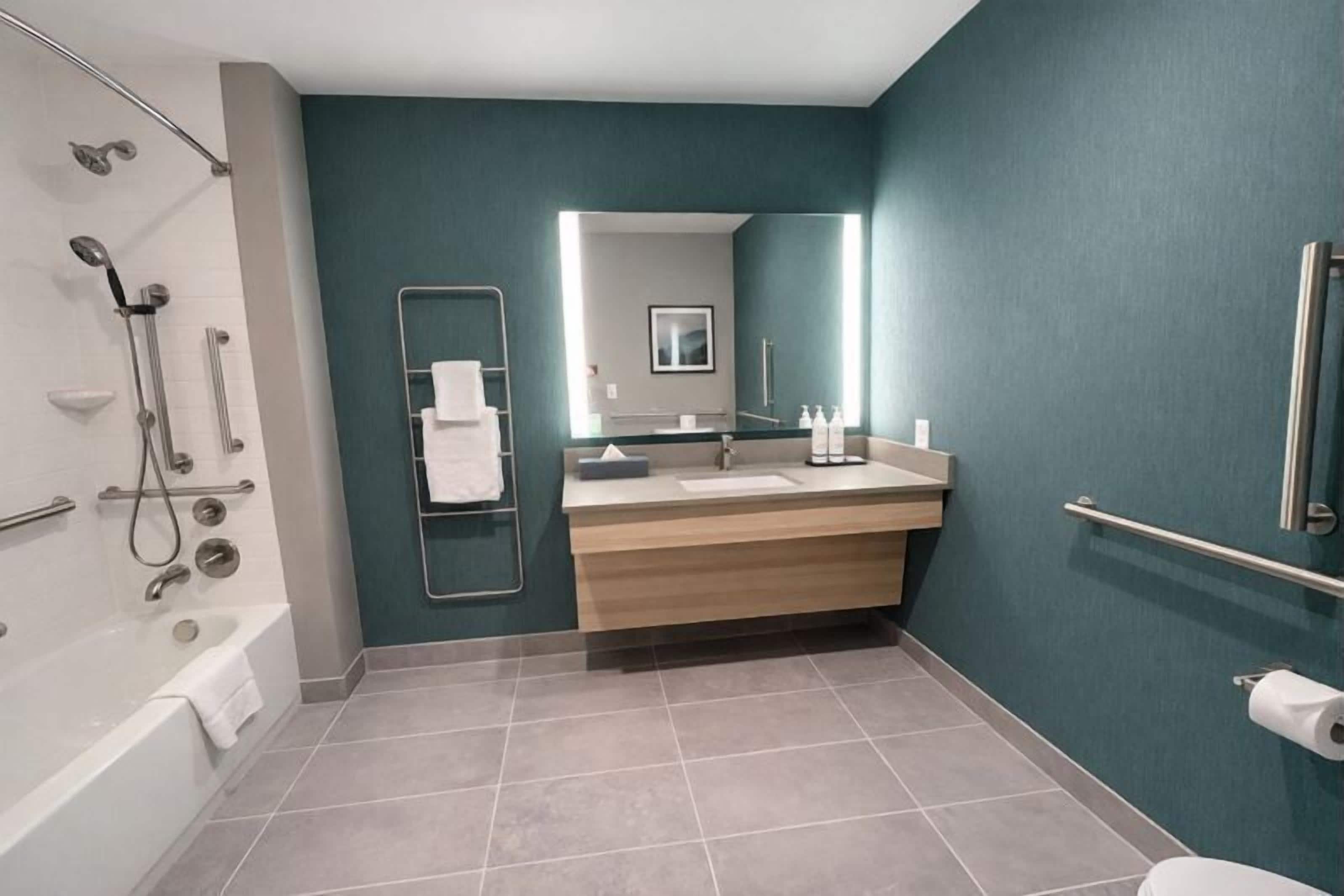 Un baño moderno con bañera, ducha y tocador con espejo.