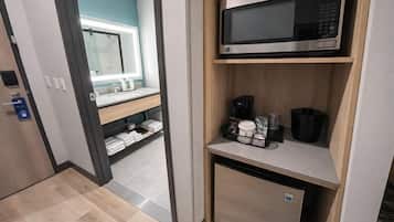 Ein Hotelzimmer mit Mikrowelle auf einem Regal, einer Kaffeemaschine und einem kleinen Kühlschrank.