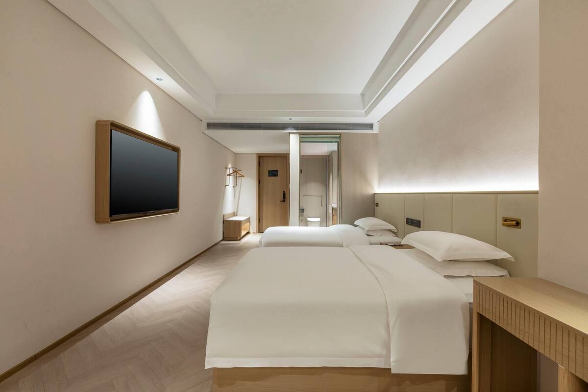 Una camera d'albergo con un letto grande, comodini, una TV e un'uscita che conduce al bagno.