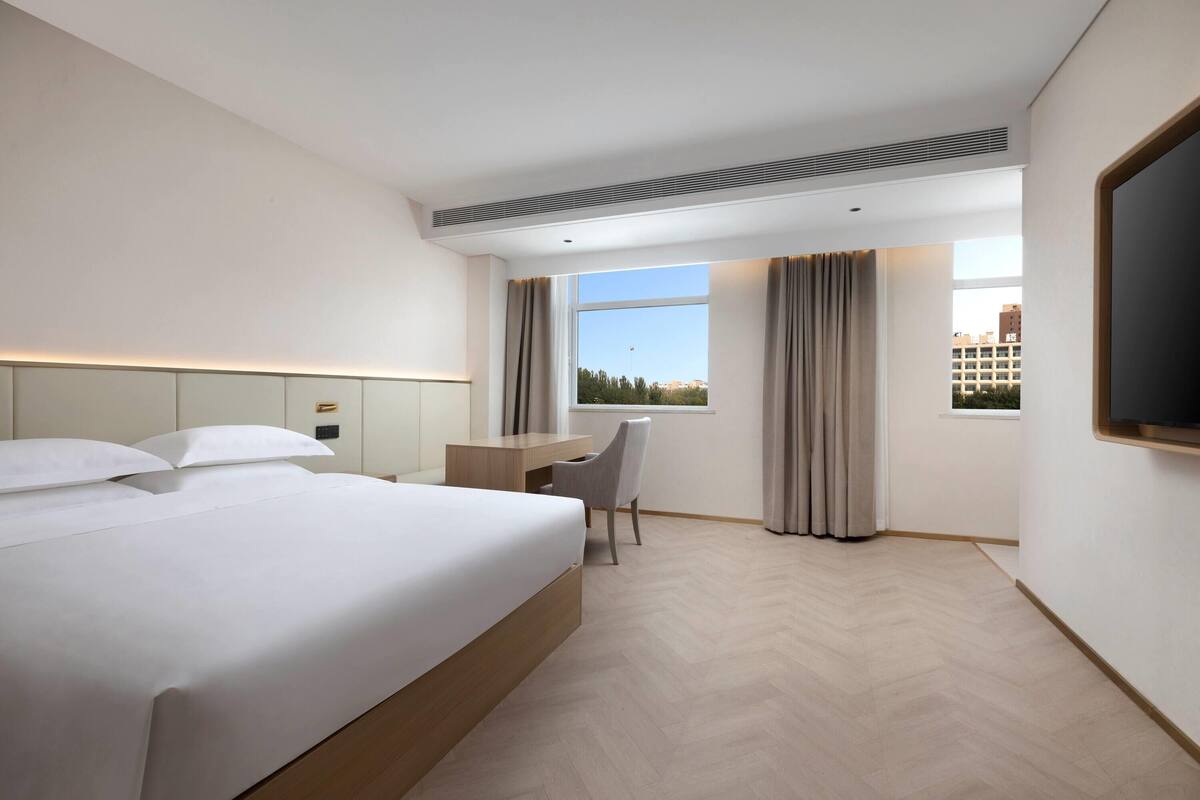 Una camera d'albergo con un grande letto, una scrivania, una sedia e una televisione.