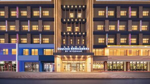 Ett hotell med en modern fasad, flera våningar och en framträdande entré med glasdörrar.