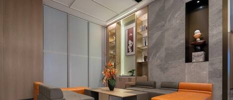 Un hall d’entrée moderne avec un canapé, des fauteuils, une table basse et un vase décoratif.