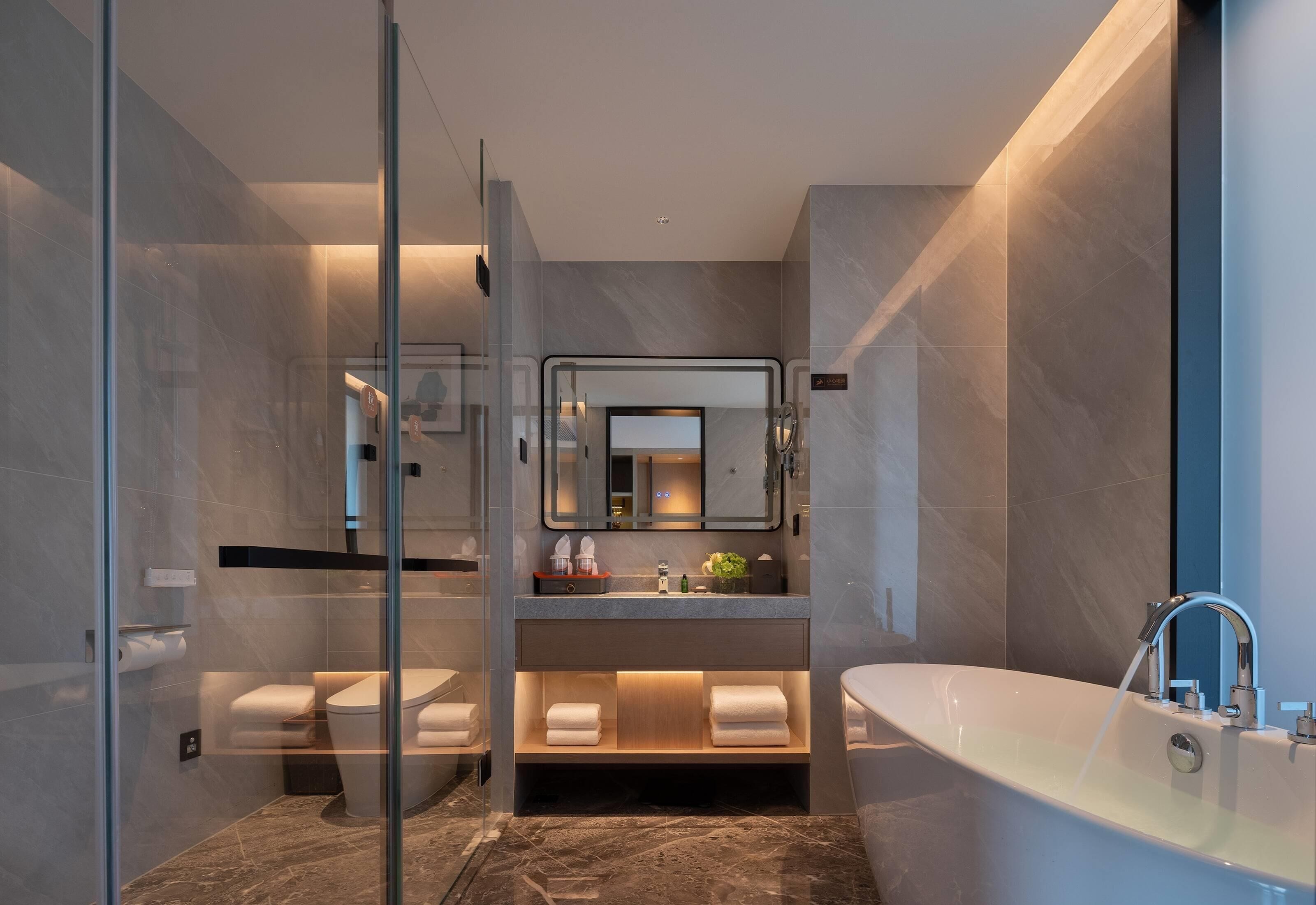A modern bathroom with a glass shower enclosure, a vanity with a mirror, and a freestanding bathtub.