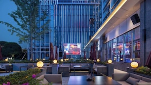 An outdoor seating area with tables and chairs, surrounded by greenery and illuminated by spherical lights. - Howard Johnson Airport Hotel Changsha (Changsha)