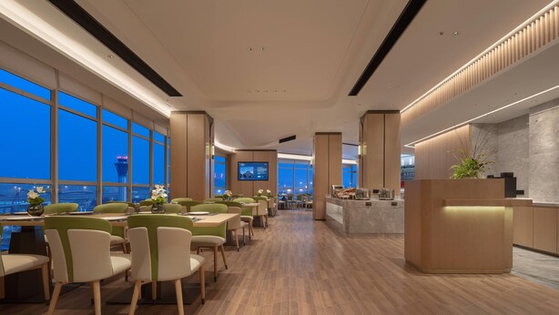 A modern hotel lobby with a long reception desk, multiple seating areas, and large windows offering a city view. - Howard Johnson Airport Hotel Changsha (Changsha)