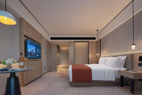 A modern hotel room with a bed, bedside table, TV, and a small desk with a chair. - Howard Johnson Airport Hotel Changsha (Changsha)