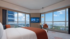 A modern hotel room with a large bed, a TV mounted on the wall, a small table with a chair, and a view of the city through large windows. - Howard Johnson Airport Hotel Changsha (Changsha)