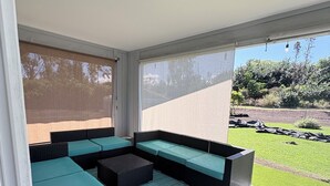A modern outdoor seating area with a sectional sofa and a small table, a blue rug, and a pair of sandals on the ground. - Spectacular Fully fenced 3 bedroom home  in Keaau with Amenities and Fast WiFi (Keaau)