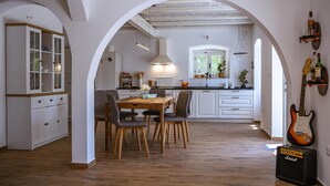 A dining area with a wooden table and chairs, white cabinetry, and a kitchen in the background. - Luxurious home in Herceg Novi (Herceg Novi)