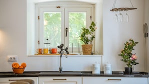 A kitchen with a window, a sink, a coffee maker, and a bowl of oranges. - Luxurious home in Herceg Novi (Herceg Novi)