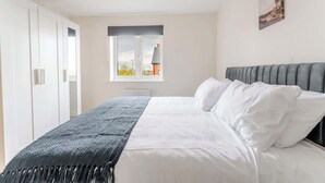 A bedroom with a bed, a window with a view, a wardrobe, and a painting on the wall. - Spacious 4 Bed Contractor & Family Home, Bristol (Stoke Gifford)