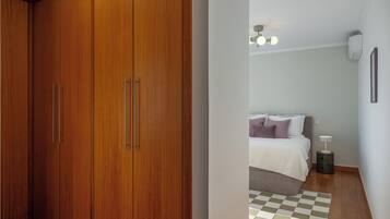 A bedroom with a bed, bedside table, and a checkered rug.