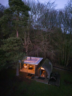 Une petite cabane avec un toit en pente, un foyer et une terrasse.