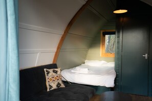 A cozy room with a bed, a couch, a window, and a door. - Luxury Cabin with Pergola in Rural Hampshire (Chawton)