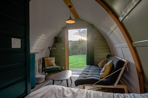 L’intérieur d’un chalet accueillant, doté d’un toit incurvé, avec un canapé, une petite table et une chaise.