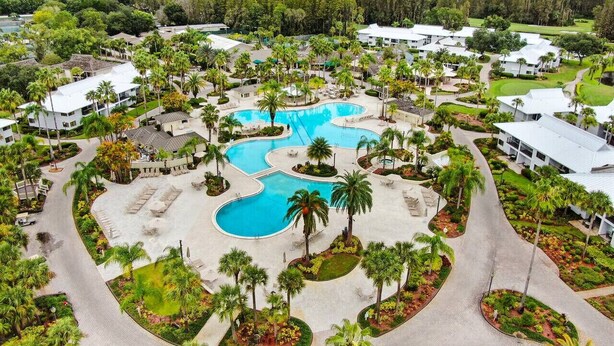 A resort with multiple swimming pools, palm trees, and a golf course. - Relaxation Starts Here (Zephyrhills)