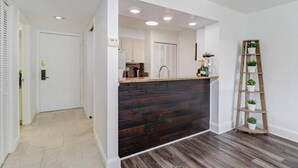 A modern kitchen with dark wood cabinetry, a built-in island, and a wooden ladder shelf with plants. - Relaxation Starts Here (Zephyrhills)