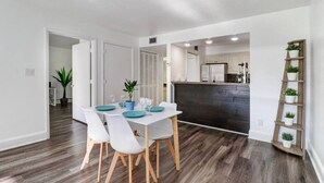 A modern dining area with a white table, teal plates, and white chairs. - Relaxation Starts Here (Zephyrhills)