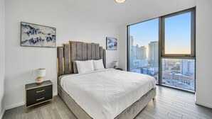 A modern bedroom with a large bed, a nightstand, a lamp, and two abstract paintings on the wall. - Cosy 3Beds/3Baths High Floor Unit Heart Of Miami (Miami)