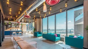 Een moderne lounge met zitplaatsen, een bar en grote ramen met uitzicht op de stad.