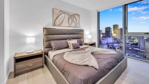 Een moderne slaapkamer met een groot bed, stadszicht en een minimalistisch design.