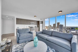A modern living room with a gray sofa, a round coffee table, and a view of a cityscape through large windows. - Stunning High Floor 3 Bedrooms Unit Downtown Miami (Miami)