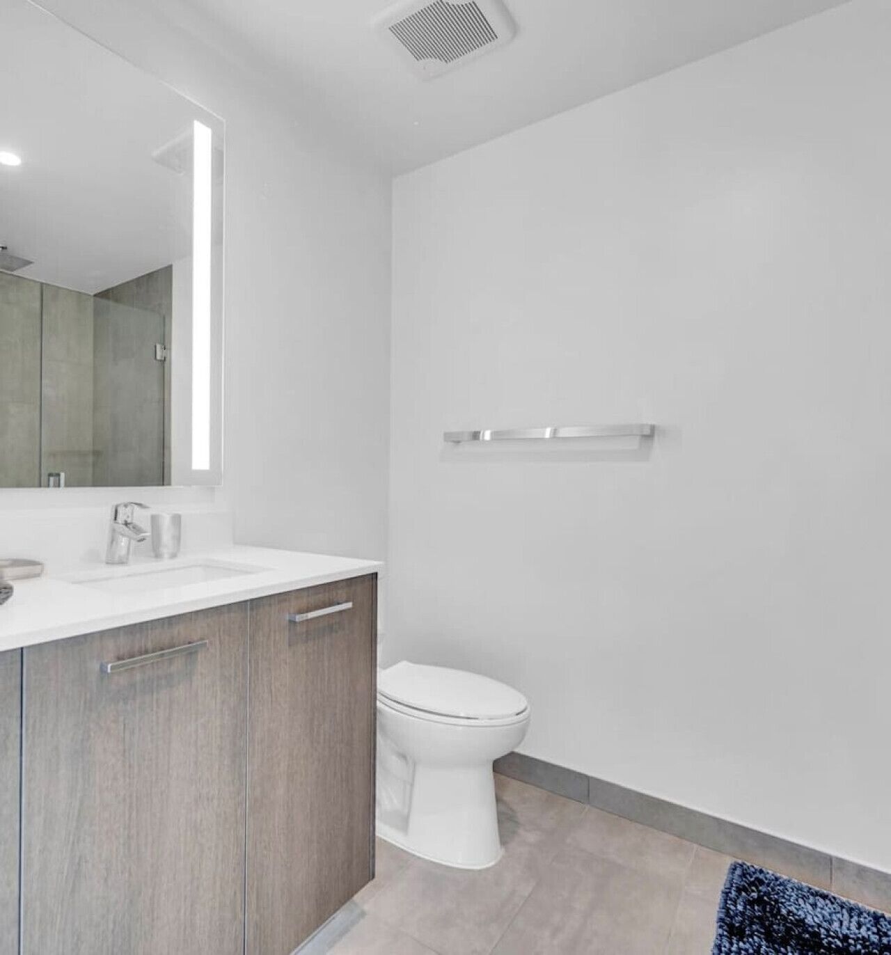 Een moderne badkamer met een wit wastafel, toilet en spiegel.