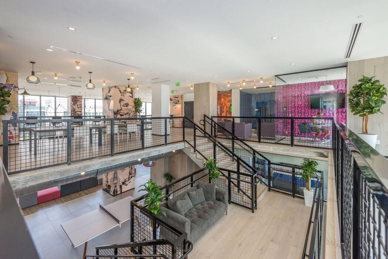 Un vaste espace intérieur comprenant plusieurs coins salon, un escalier et une vue sur l ’extérieur.