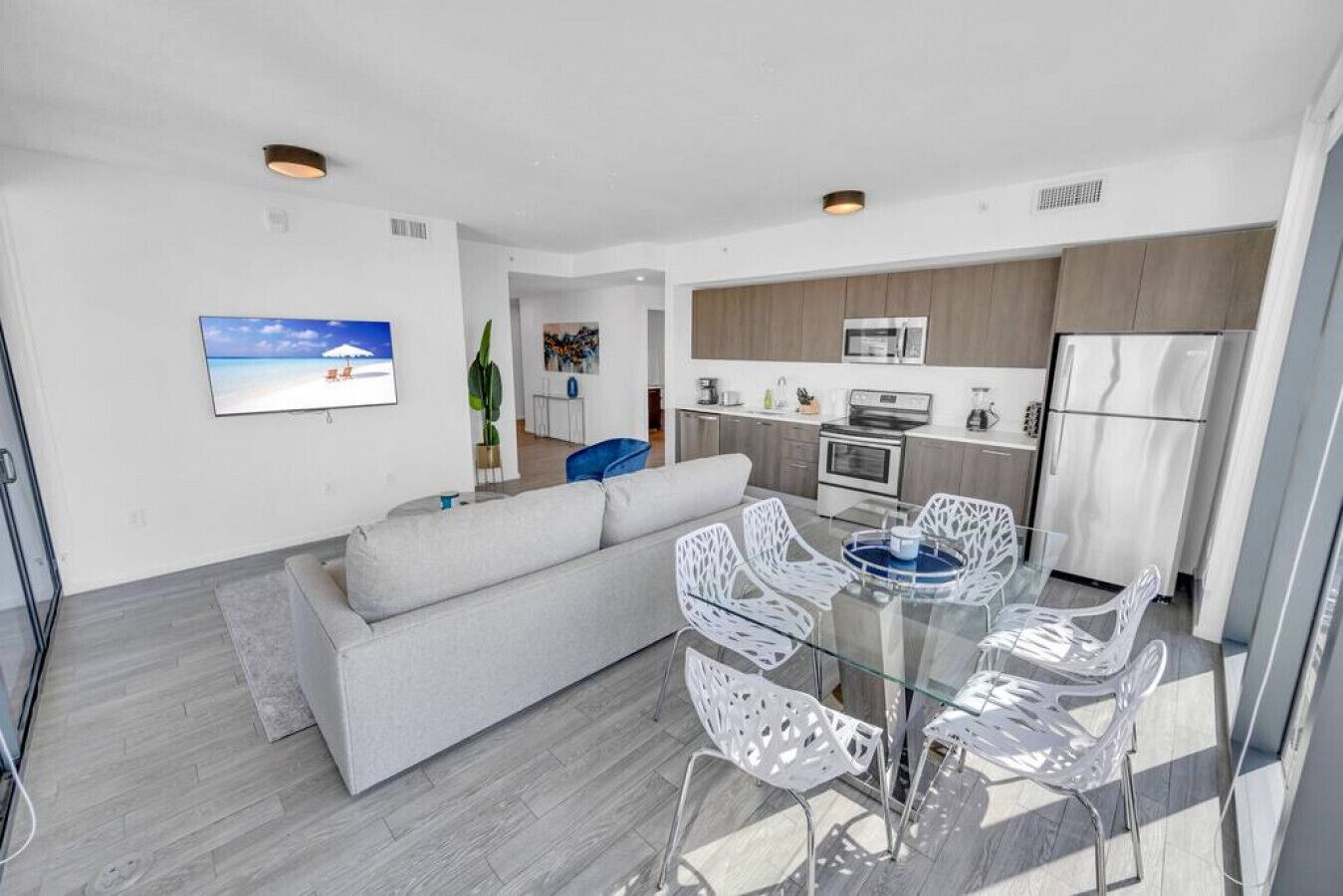 A modern apartment with a living area featuring a sofa and a glass dining table with chairs.