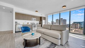 Eine moderne Wohnung mit Wohnzimmer, Küche und großen Fenstern mit Blick auf die Stadt.