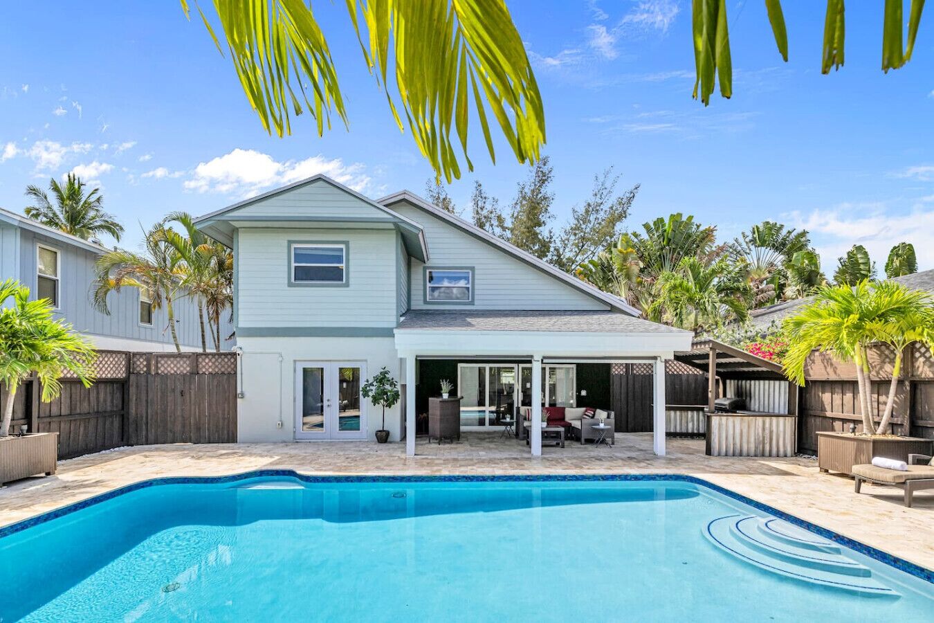 A two-story house with a swimming pool, a covered patio, and a fenced backyard.