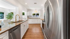 Una cocina moderna con armarios blancos, electrodomésticos de acero inoxidable y encimera de madera.