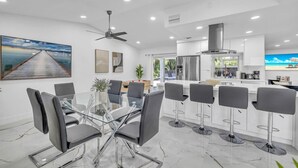 A modern kitchen with white cabinets, a central island, and bar stools. - Amazing house with pool (Delray Beach)