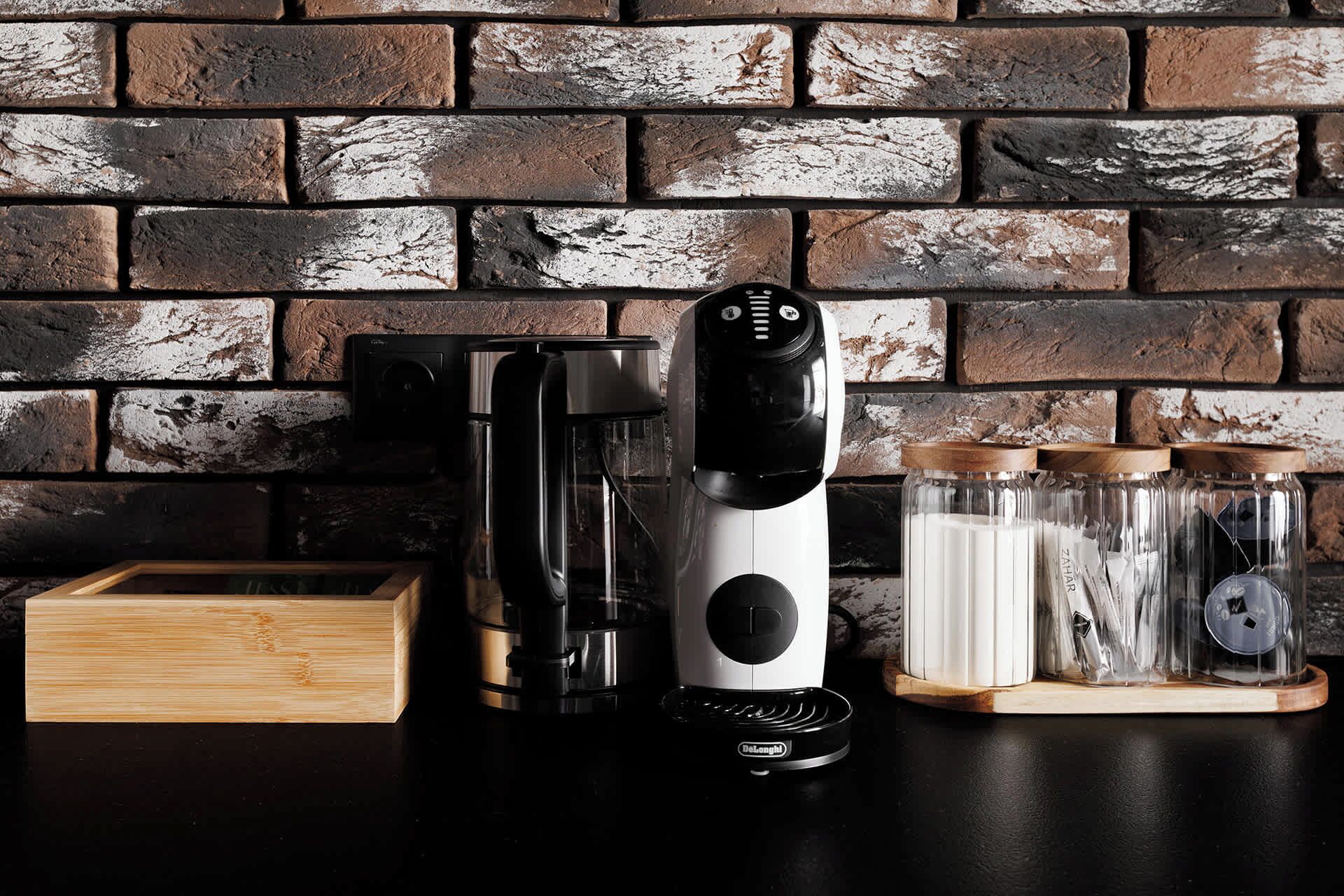 A kitchen with a coffee maker, a blender, and jars on a wooden shelf.