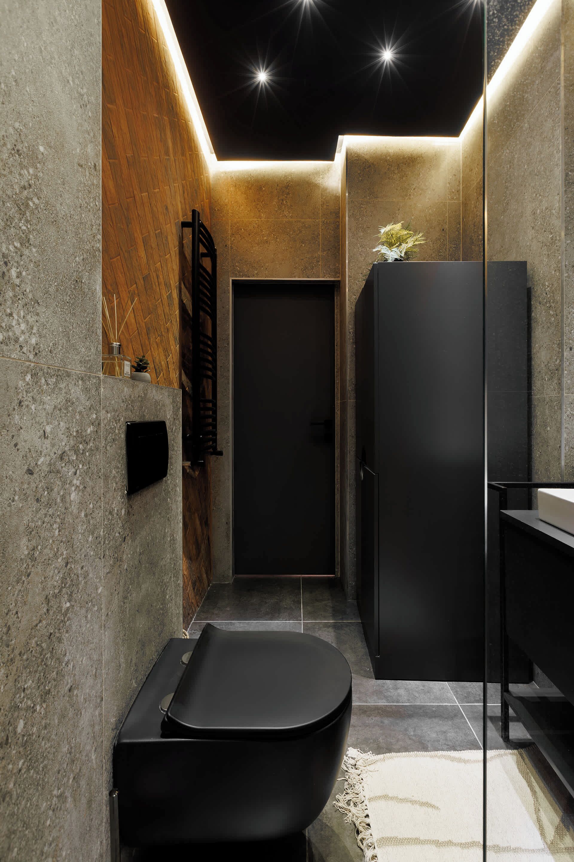 Une salle de bain moderne avec une baignoire noire, un mur d’accent en bois et un grand miroir.