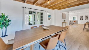 Et moderne spiseområde med et træbord, stole og et stort vindue med gardiner.