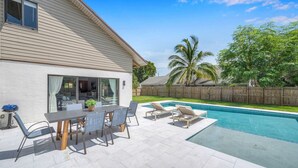 Een huis met een terras, een zwembad en een houten omheining.