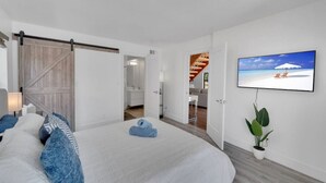 Een slaapkamer met een bed, een schuifdeur, een televisie en een plant.