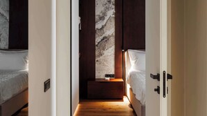 Una camera da letto moderna con pavimento in legno, parete decorata con marmo e comodino con lampada.