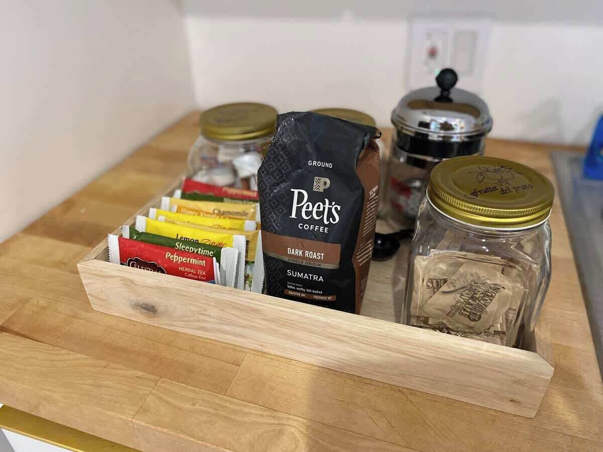 Un vassoio di legno con una confezione di caffè Peet's, bustine di tisana e un barattolo di caffè macinato.