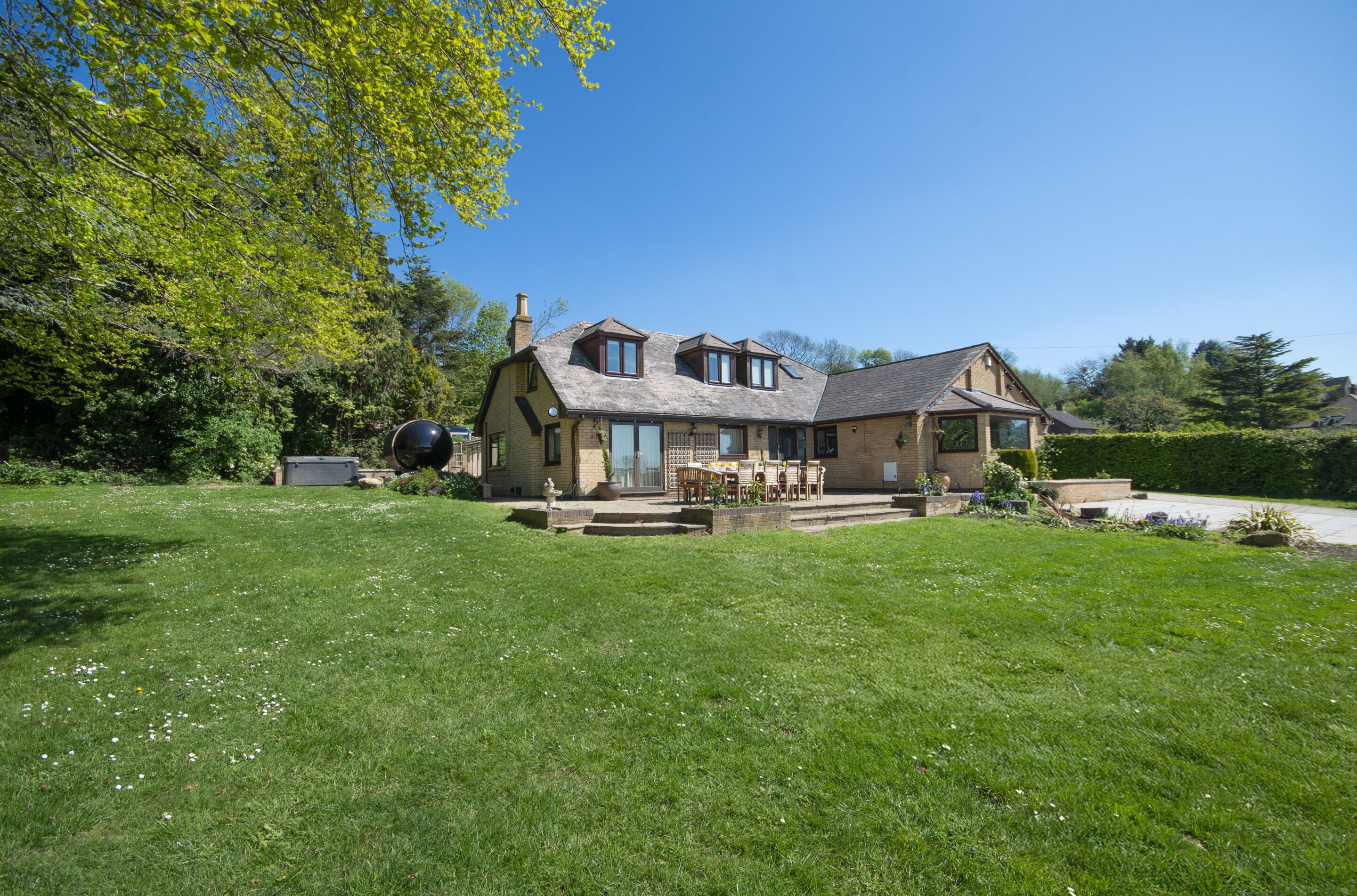 A two-story house with a patio area, surrounded by a well-maintained lawn.