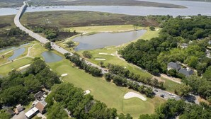 Eine Vogelperspektive auf einen Golfplatz mit mehreren Teichen, einer Brücke und Wohngebieten.