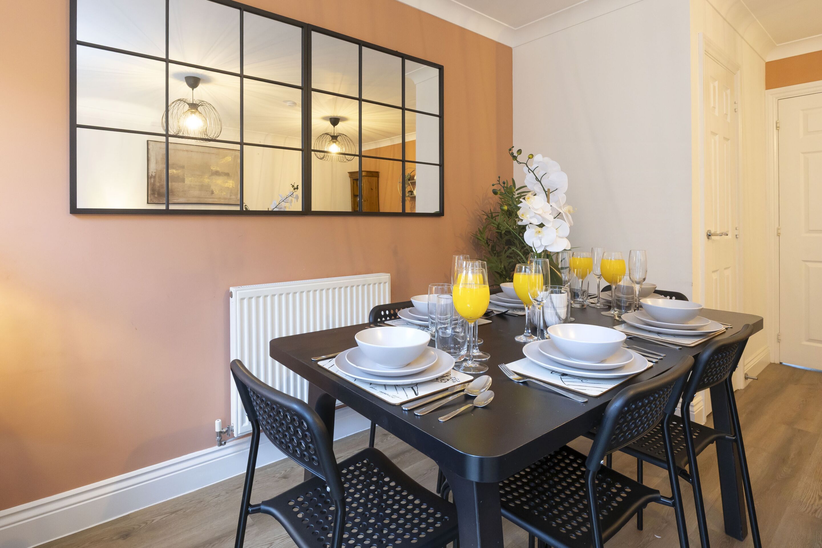 A dining area with a table set for four, including plates, bowls, glasses, and cutlery.